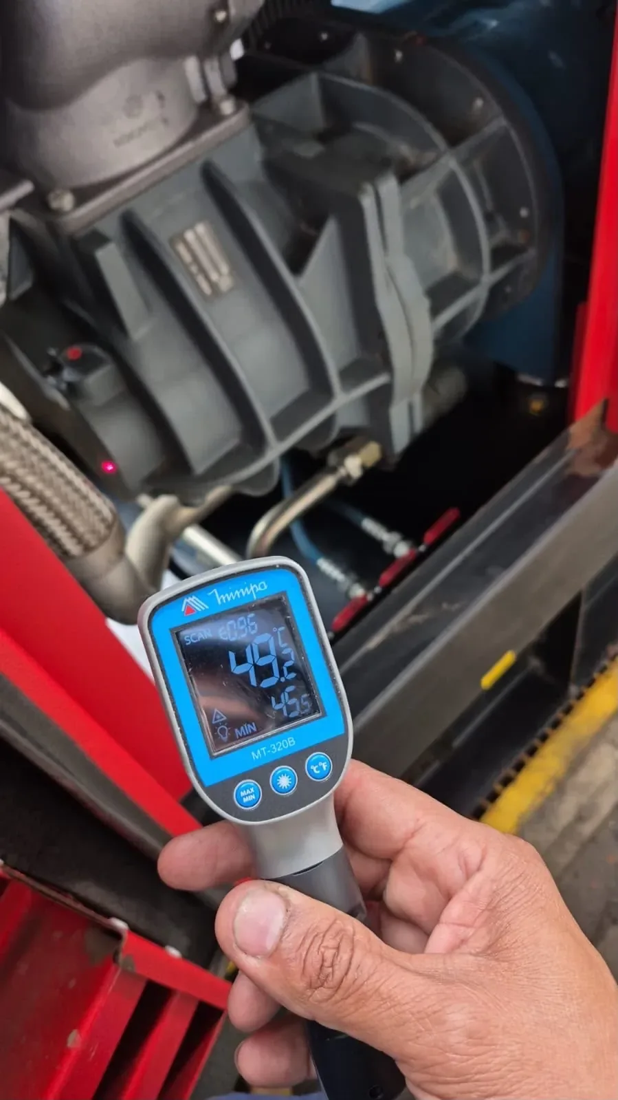 Técnico monitorando compressor de ar com termômetro infravermelho — Rental Parts
